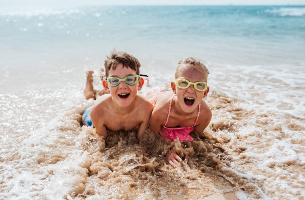 Children holding their breath and wearing goggles while swimming underwater in a saltwater ocean, enjoying the clear view and playful environment.