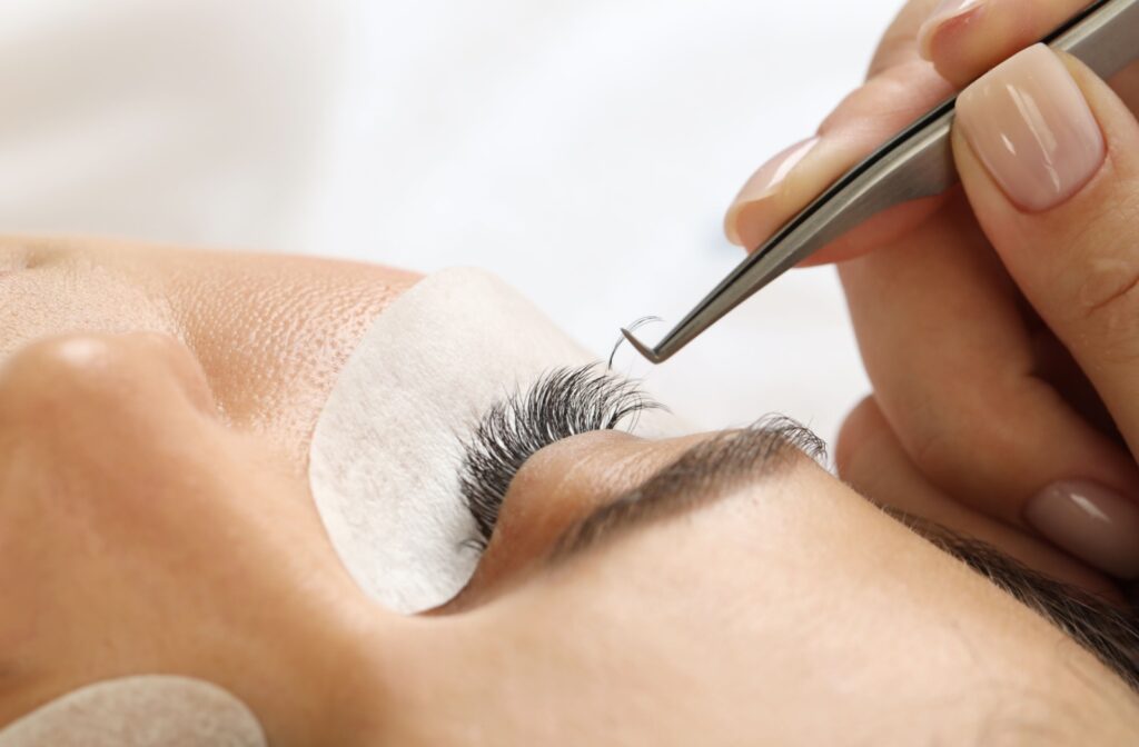 Close-up of a person receiving eyelash extensions from a technician.