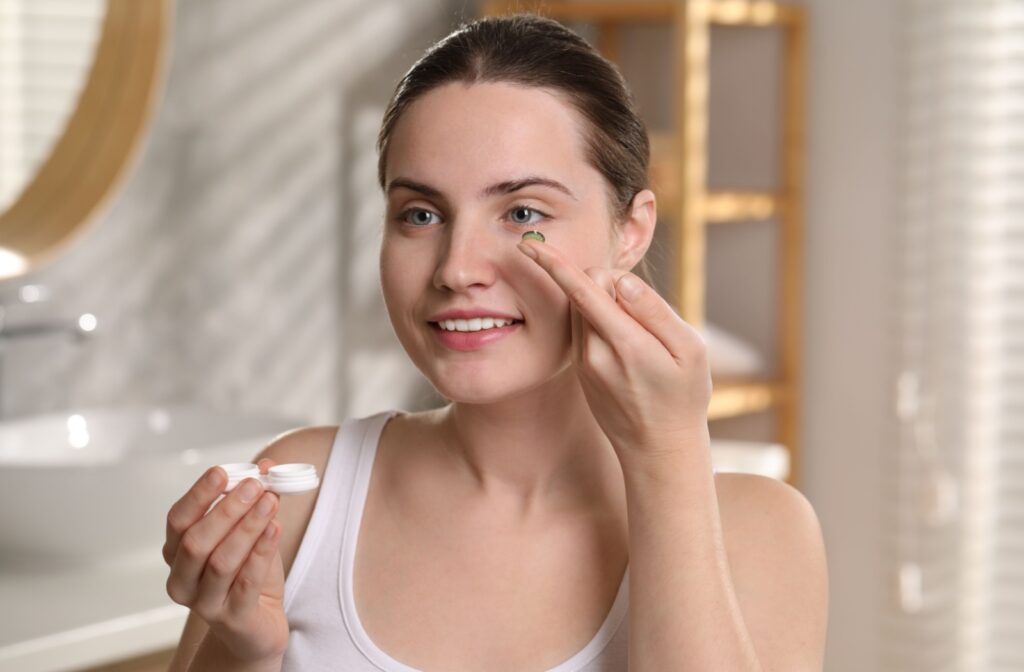 A person looking in the mirror, about to put a contact lens into their eye.