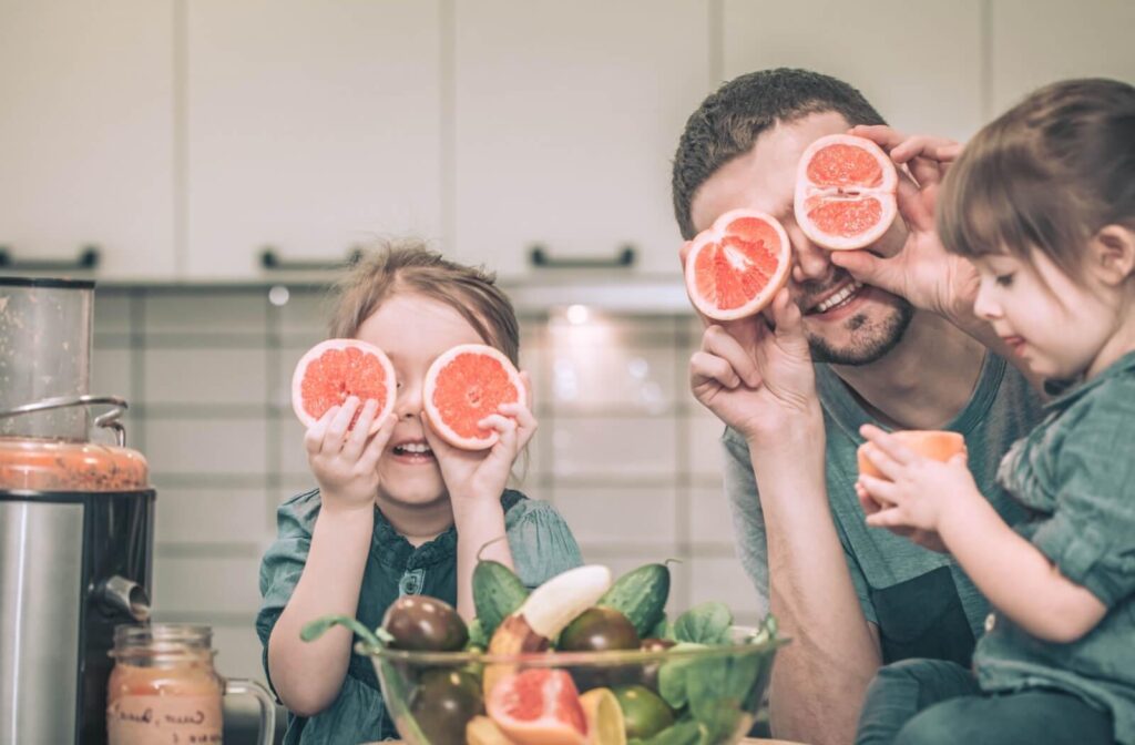 A family holding up grapefruit in front of their eyes, symbolizing how nutrition and diet affect eye health.